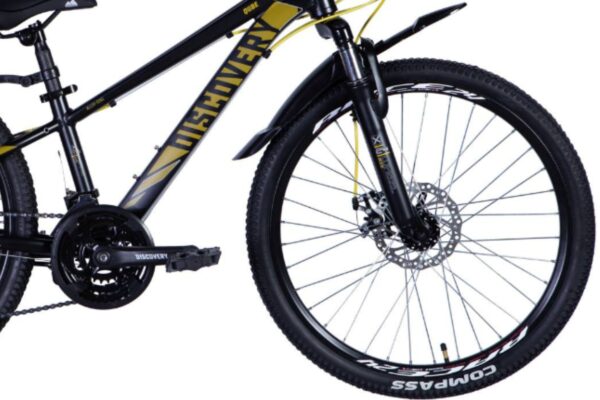 Svart mountainbike med gul text, närbild av framhjulet.