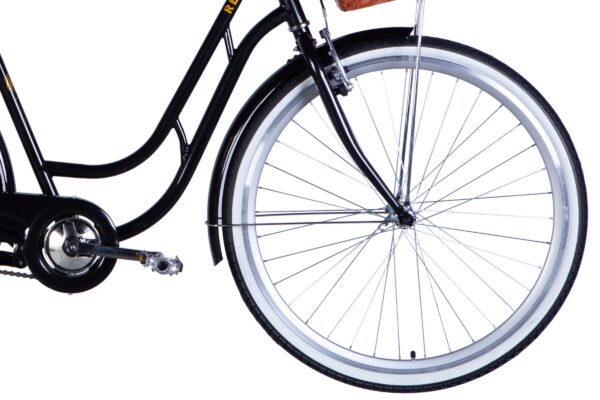 Svart cykel med korg och pedaler på nära håll.