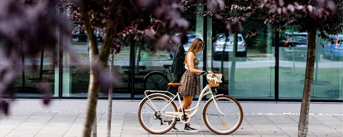 Kvinna med cykel vid byggnad med fönster.